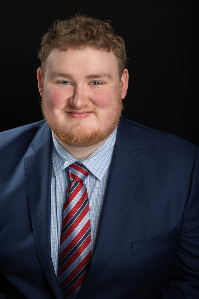 A navy suit and patterned tie give this studio headshot a classic, composed look for business use.
