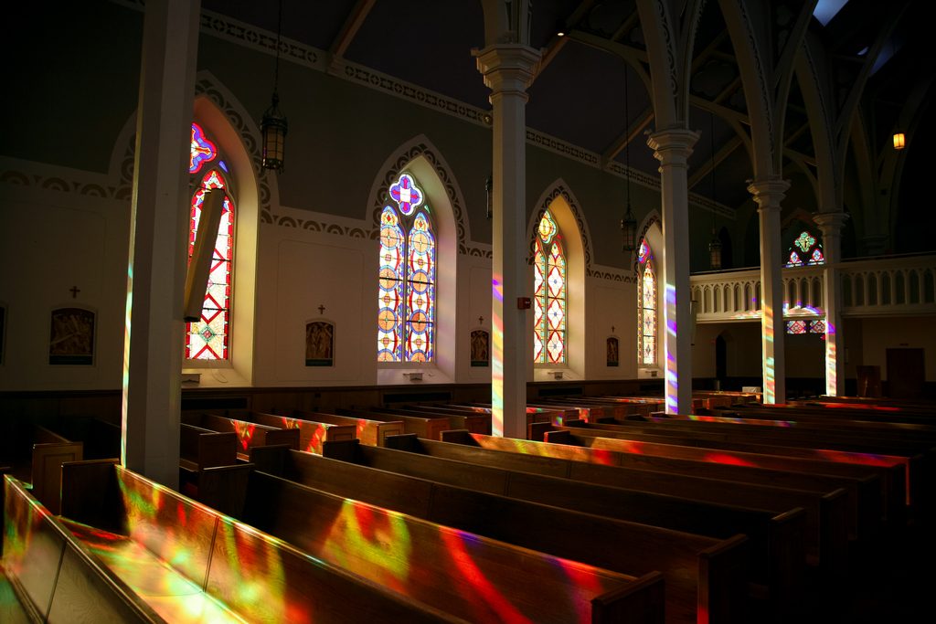 Colorful reflections coming into a church from sunlit stainglass in church wedding in Rutland, Vermont.